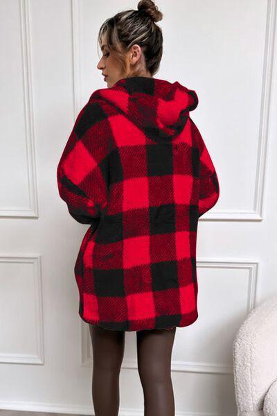 a woman standing in front of a door wearing a red and black checkered coat