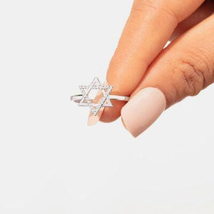 a woman's hand holding a ring with a star of david on it