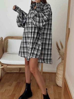 a woman wearing a black and white plaid shirt dress