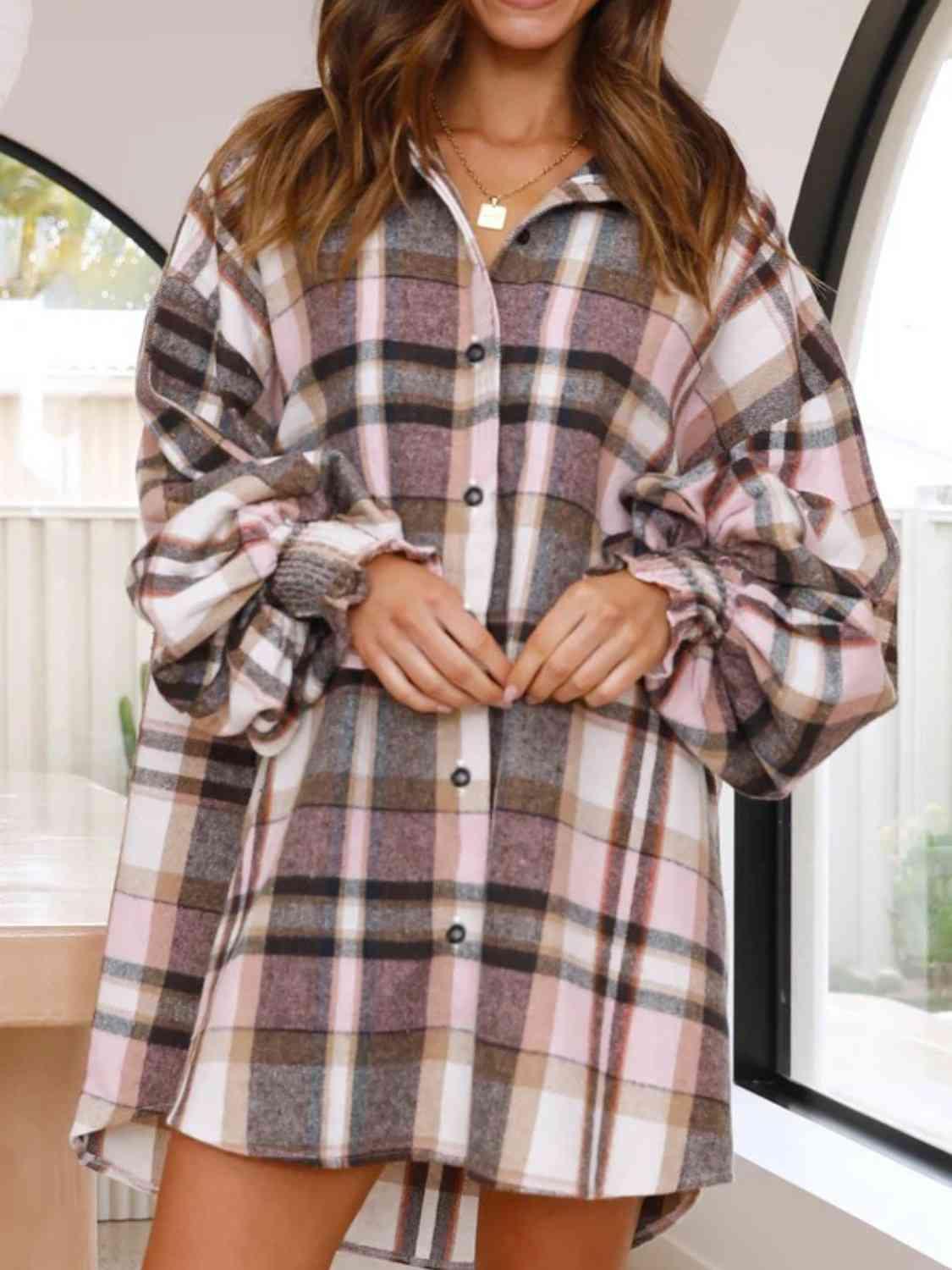 a woman standing in front of a window wearing a plaid shirt dress