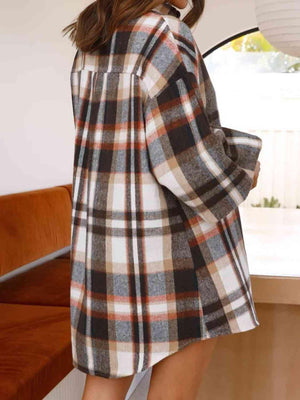 a woman in a plaid coat is standing by a window