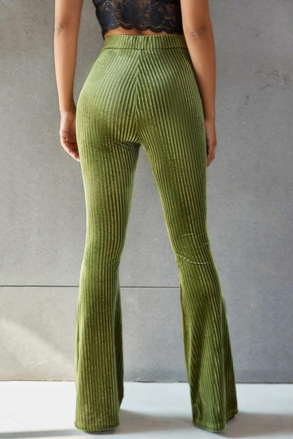 a woman in a black top and green pants