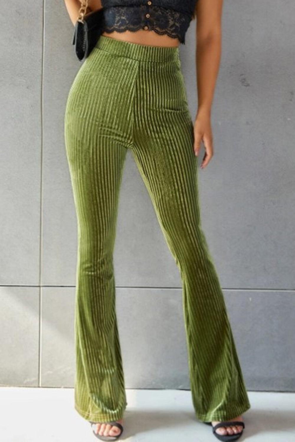 a woman in a black top and green pants