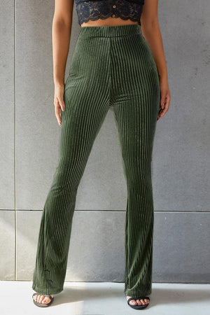 a woman wearing a crop top and green pants