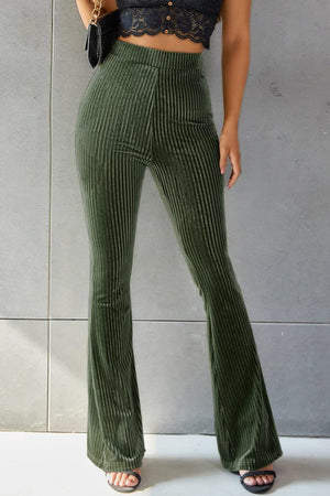 a woman wearing a crop top and green pants