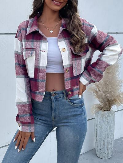 a woman standing next to a plant wearing a plaid jacket