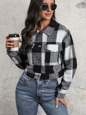 a woman holding a cup of coffee and wearing a plaid shirt