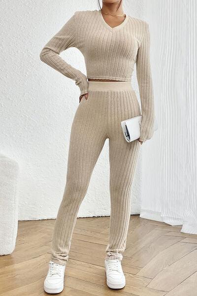 a woman standing in a room wearing a sweater and pants