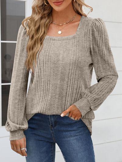a woman wearing a tan sweater and jeans