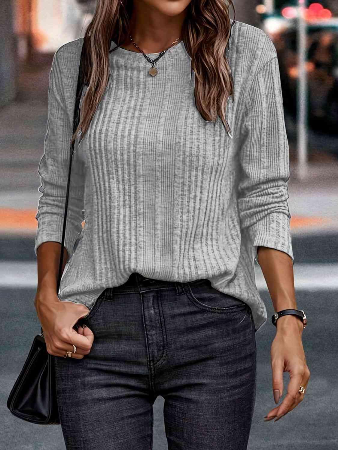 a woman wearing a gray sweater and black jeans