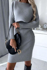 a woman in a gray sweater dress holding a black purse