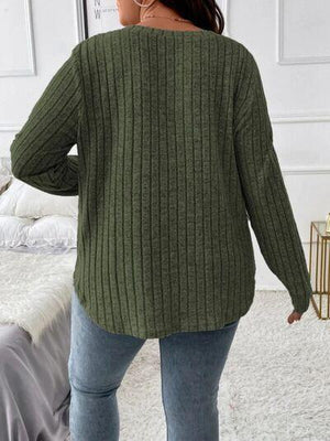 a woman standing in front of a bed wearing a green sweater