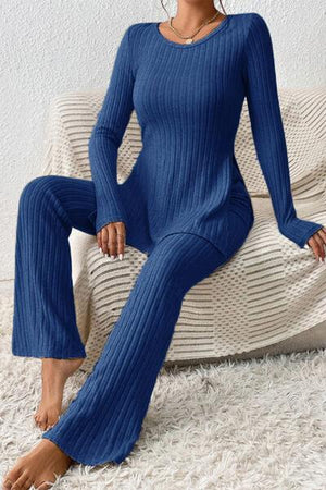 a woman sitting on a couch wearing a blue sweater and pants