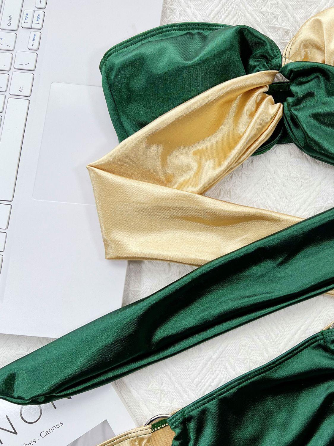 a pair of green and gold bikinis sitting on top of a laptop