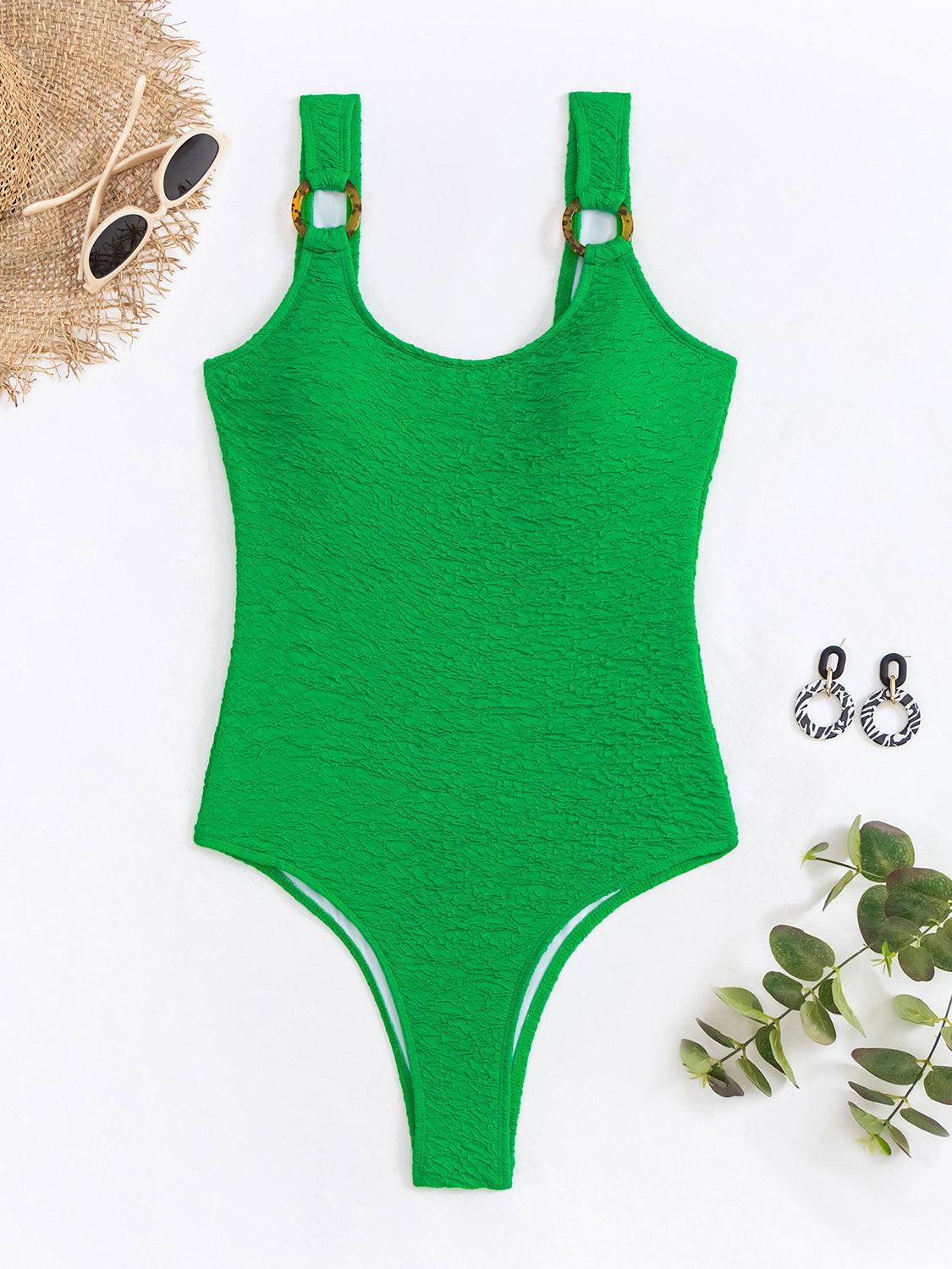 a green one piece swimsuit next to a plant