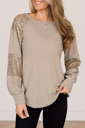 a woman wearing a tan top with sequins on it