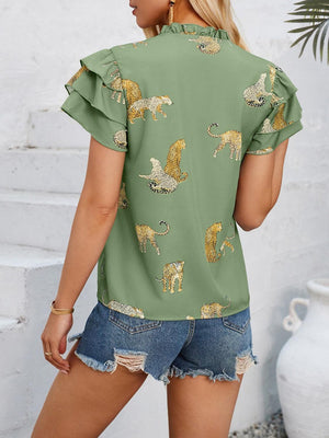 a woman wearing a green top with gold leopards on it