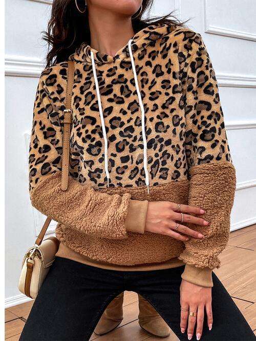 a woman wearing a leopard print hoodie and black pants
