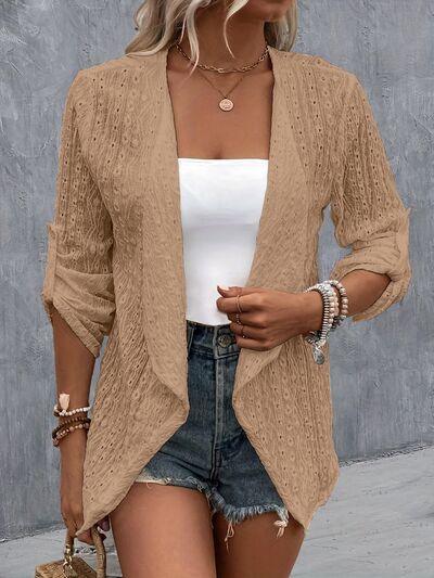 a woman wearing a tan cardigan sweater and denim shorts