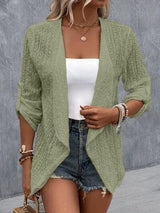 a woman wearing a green cardigan sweater and denim shorts