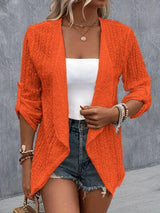 a woman wearing an orange cardigan sweater and denim shorts