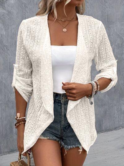 a woman wearing a white cardigan sweater and denim shorts