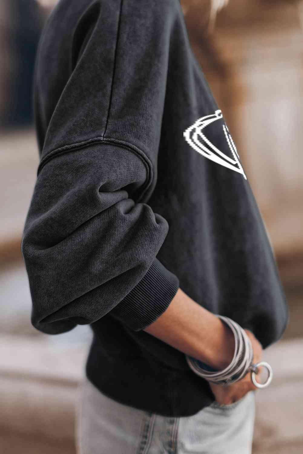 a woman wearing a black sweatshirt with a white logo on it