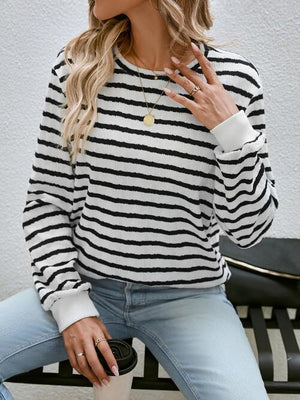 a woman sitting on a bench wearing a black and white striped sweater