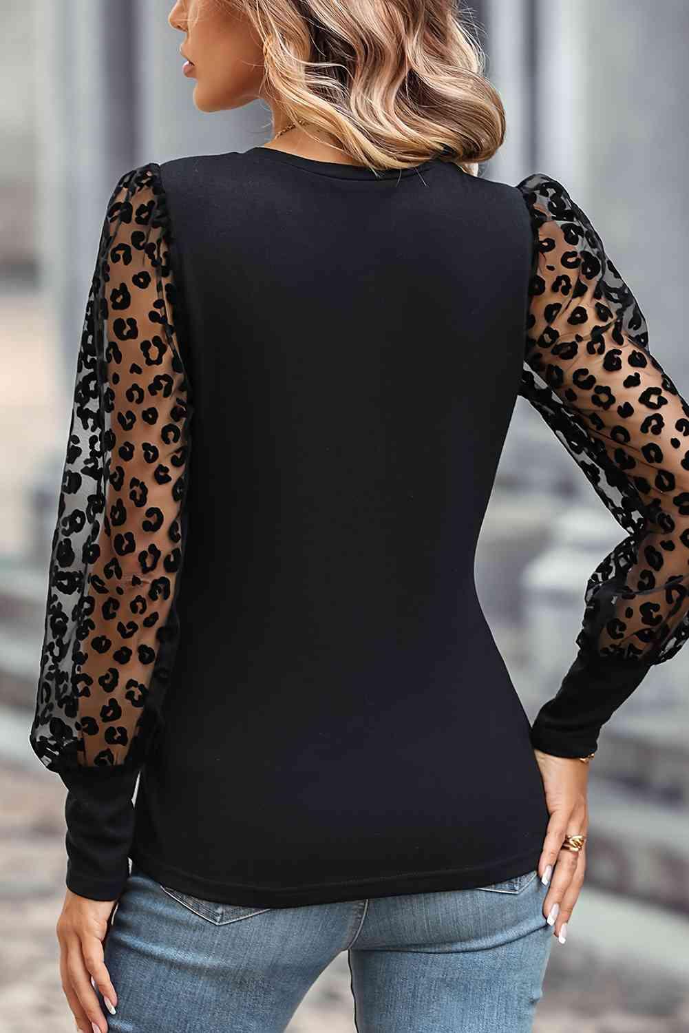 a woman wearing a black top with leopard print sleeves