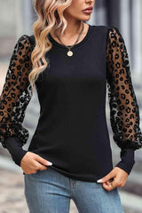 a woman wearing a black top with leopard print sleeves