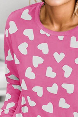 a woman wearing a pink shirt with white hearts on it
