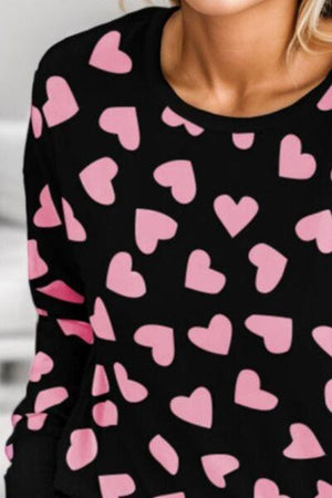 a woman wearing a black top with pink hearts on it