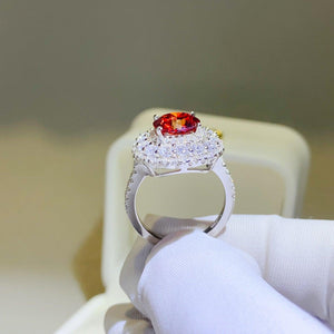 a person holding a ring with a red stone in it