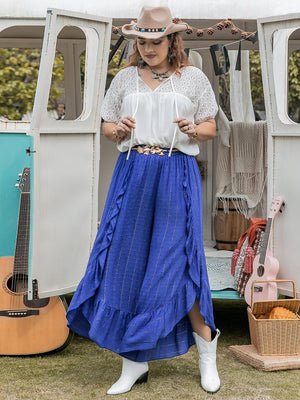 a woman in a long blue skirt standing in front of a bus