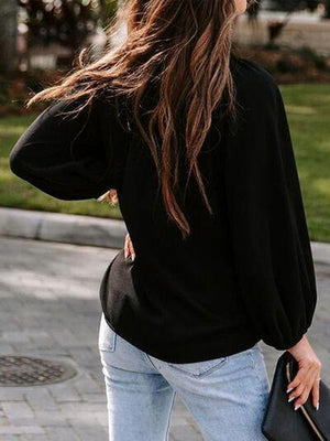 a woman walking down a sidewalk carrying a black purse