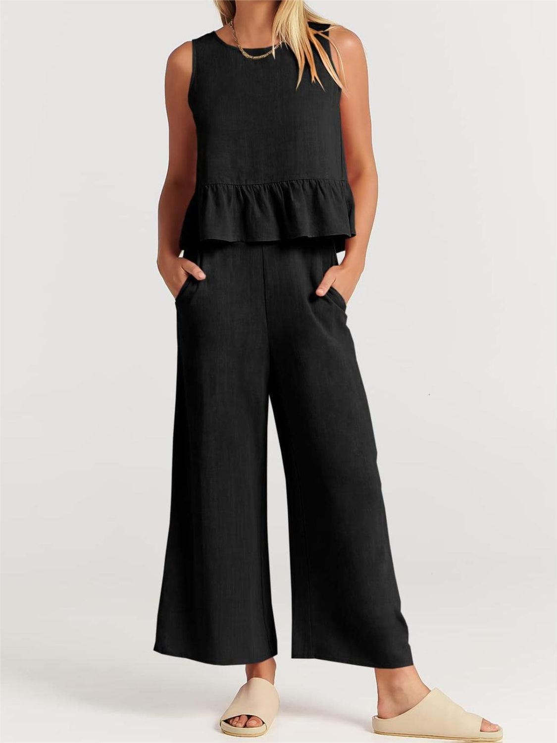 a woman wearing a black top and wide legged pants