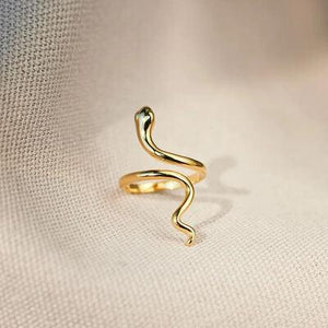 a gold snake ring sitting on top of a white cloth