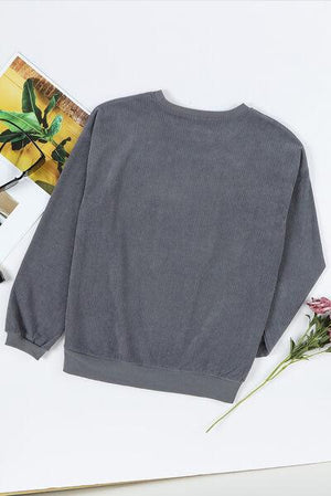 a gray sweater sitting on top of a white table