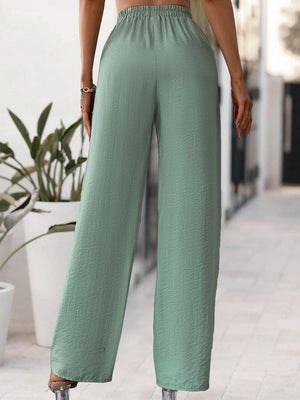 a woman wearing a crop top and wide legged pants