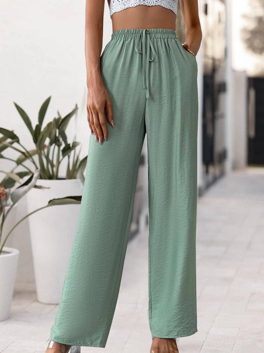 a woman wearing a crop top and green pants