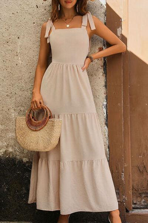 a woman standing next to a wall holding a straw bag