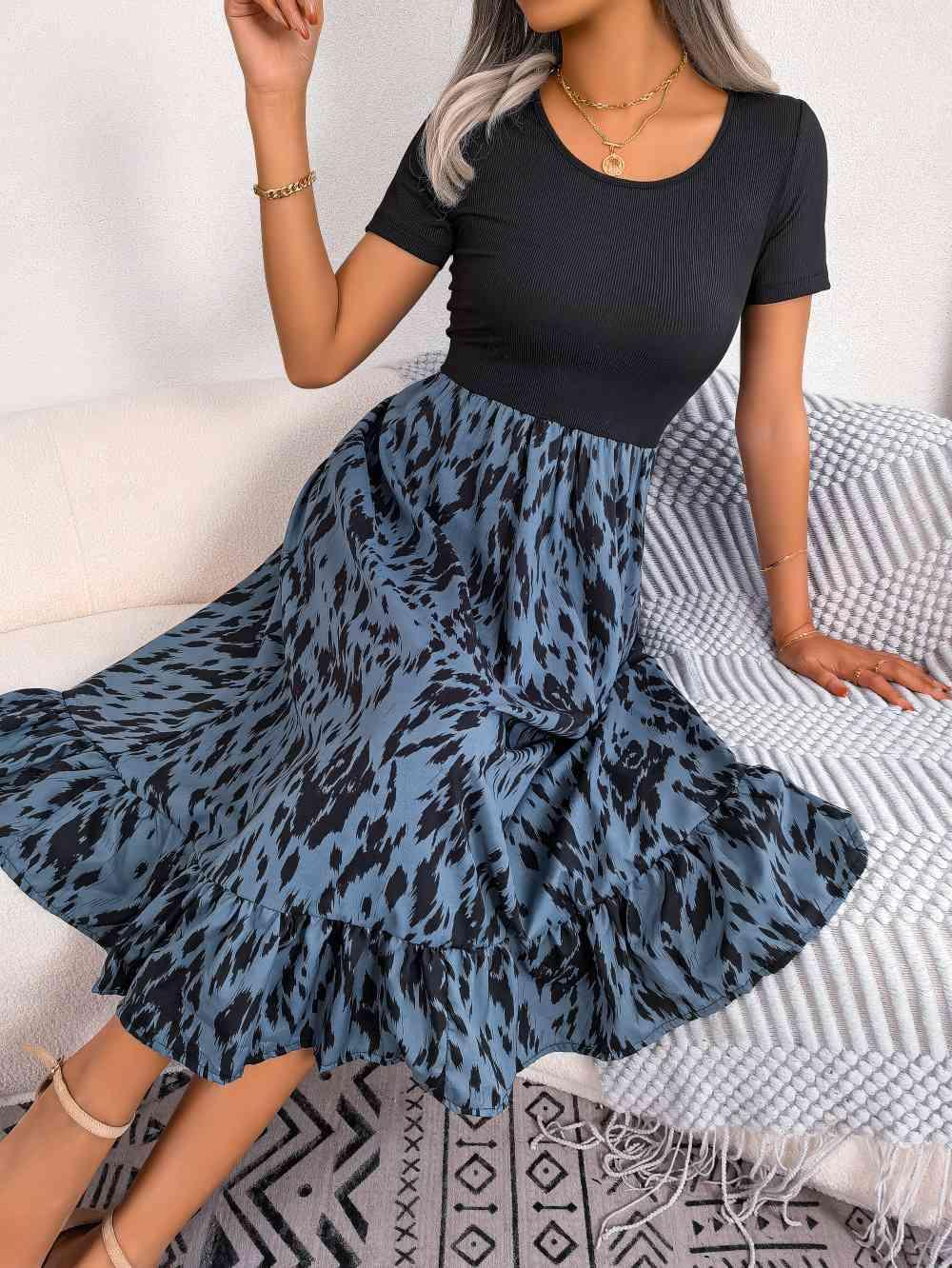 a woman sitting on a bed wearing a black top and blue skirt