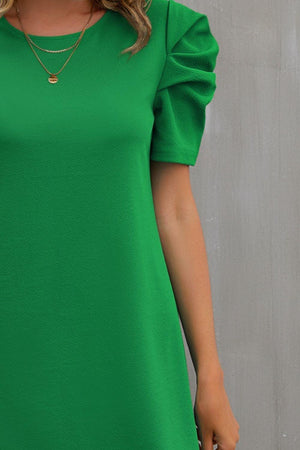 a woman wearing a green dress with a frilly sleeve