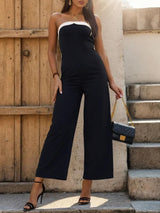 a woman in a black and white jumpsuit holding a purse