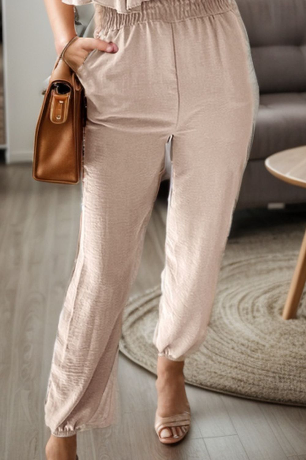 a woman standing in a living room holding a purse