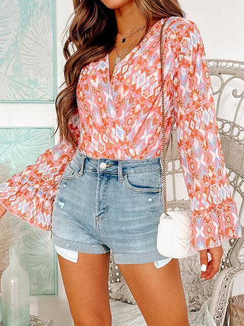 a woman wearing a floral blouse and denim shorts