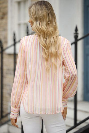 a woman with long blonde hair wearing a pink and white striped shirt