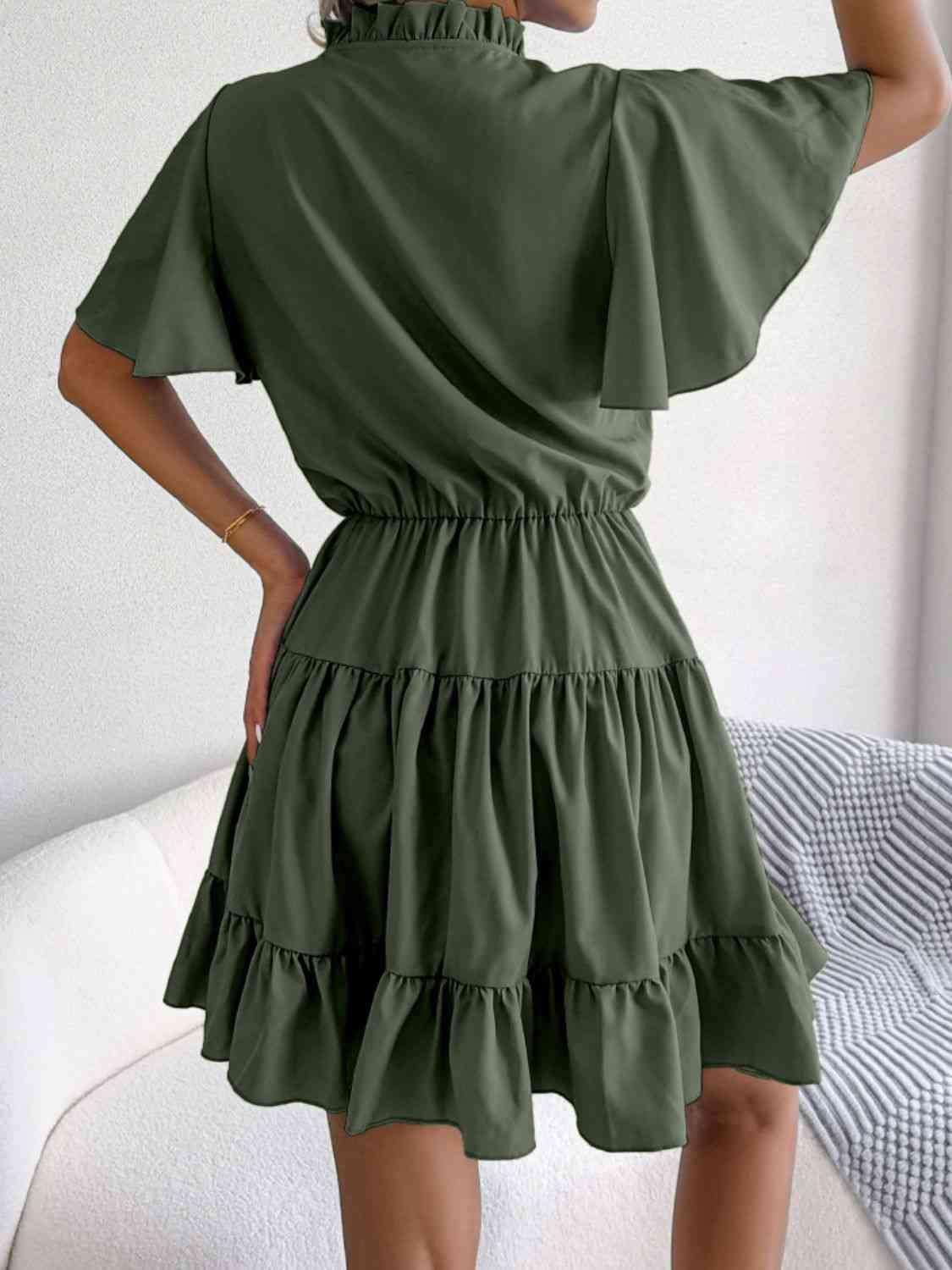 a woman wearing a green dress with ruffles