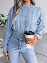 a woman wearing a blue sweater and jeans holding a coffee cup