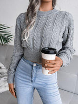 a woman wearing a gray sweater and jeans holding a cup of coffee